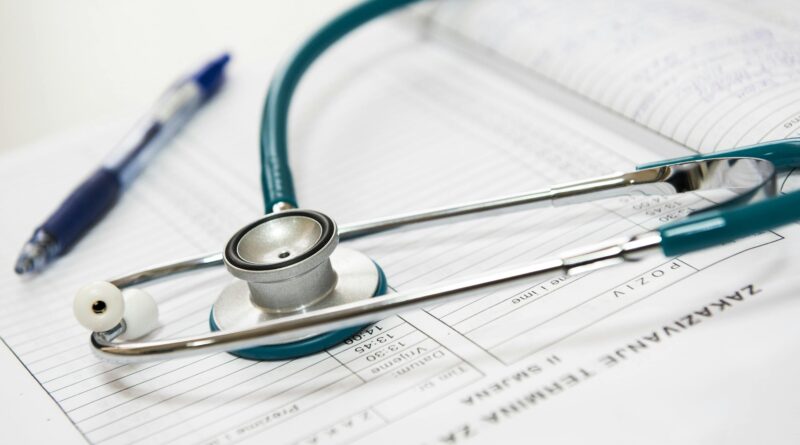 A stethoscope and pen resting on a medical report in a healthcare setting.