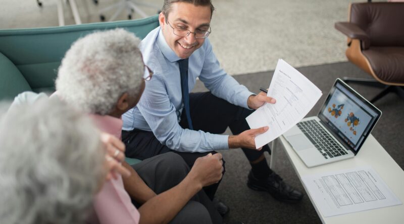 Financial advisor discussing documents with senior clients in an office setting, showcasing a collaborative consulting session.