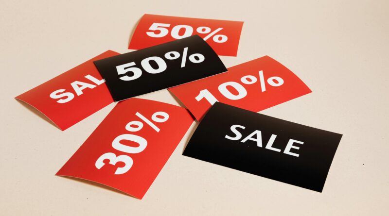 Red and black sale tags showing various discount percentages on a beige background.